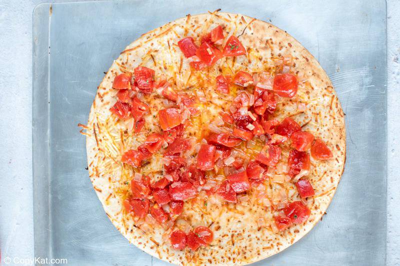 corteza de pizza cubierta con tomates y cebollas