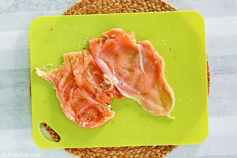 chicken breast pounded thin and seasoned on a cutting board