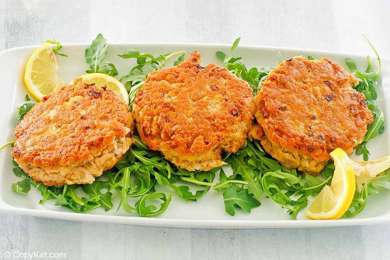 fried salmon patties, arugula, and lemon slices on a platter