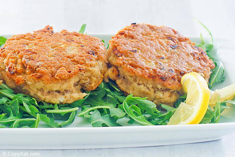 two salmon patties, lemon slice, and arugula on a plate