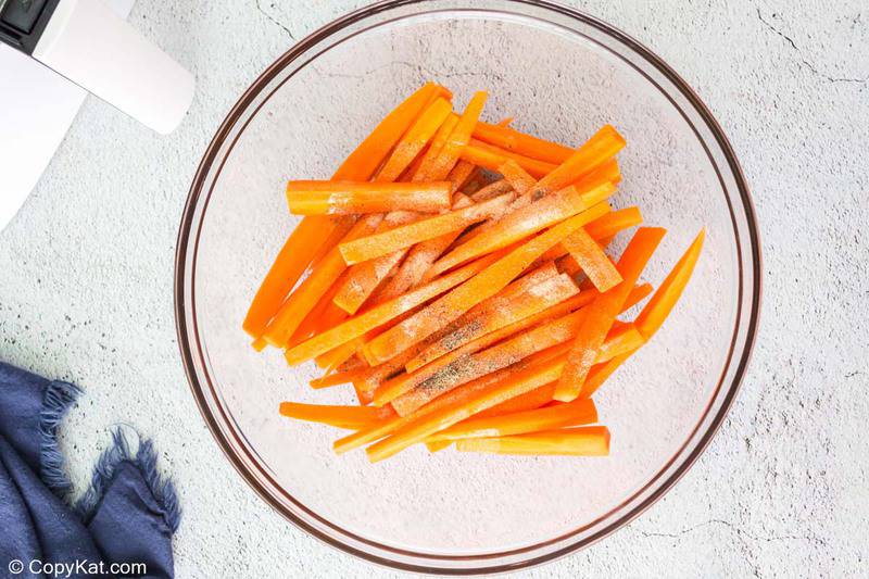 carrots sticks, oil, and seasonings in a bowl