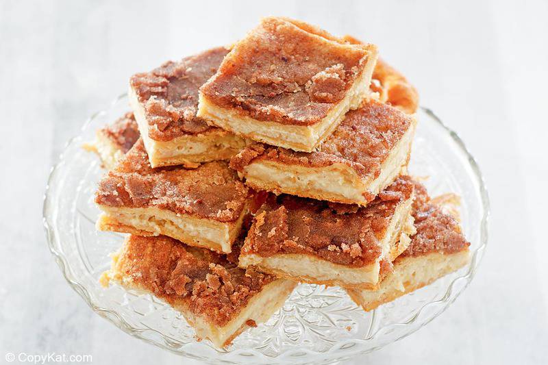 a stack of sopapilla cheesecake slices on a cake stand