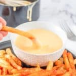 dipping a homemade Taco Bell nacho fry into cheese sauce