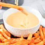 dipping a nacho fry into cheese sauce