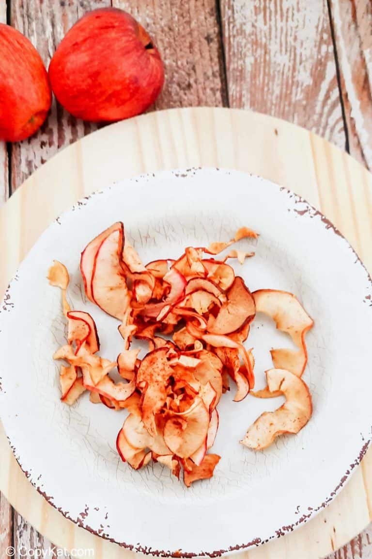 overhead view of air fryer apple chips on a plate and two apples