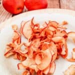 air fryer apple chips on a plate and two apples