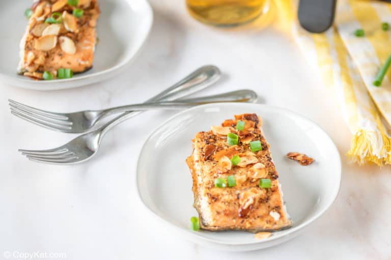 Salmon fillet topped with almonds served with lemon wedges.