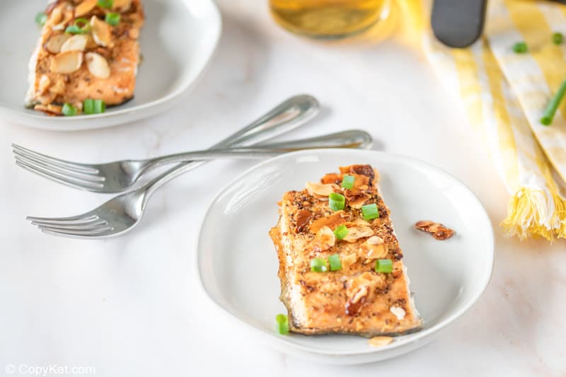air fried salmon with almonds on two plates and two forks