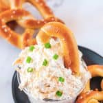 a bowl of beer cheese dip with a pretzel in it