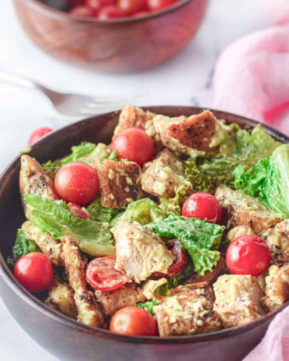 chicken Caesar salad and cherry tomatoes in wood bowls