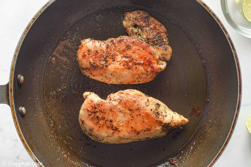 two cooked chicken breasts in a skillet
