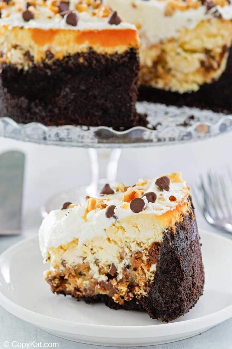 cookie dough cheesecake slice on a plate and the cheesecake on a stand