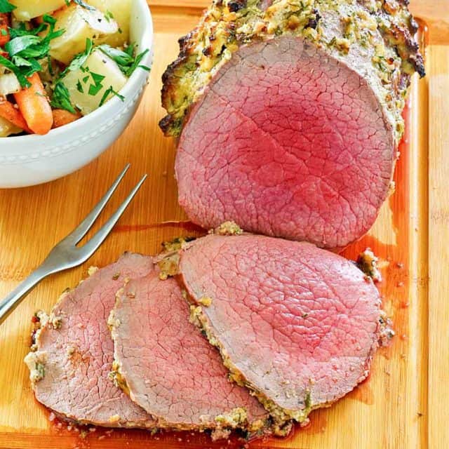 eye of round roast and a bowl of vegetables on a cutting board