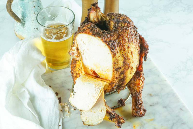 smoked beer can chicken with slices cut off and a glass of beer