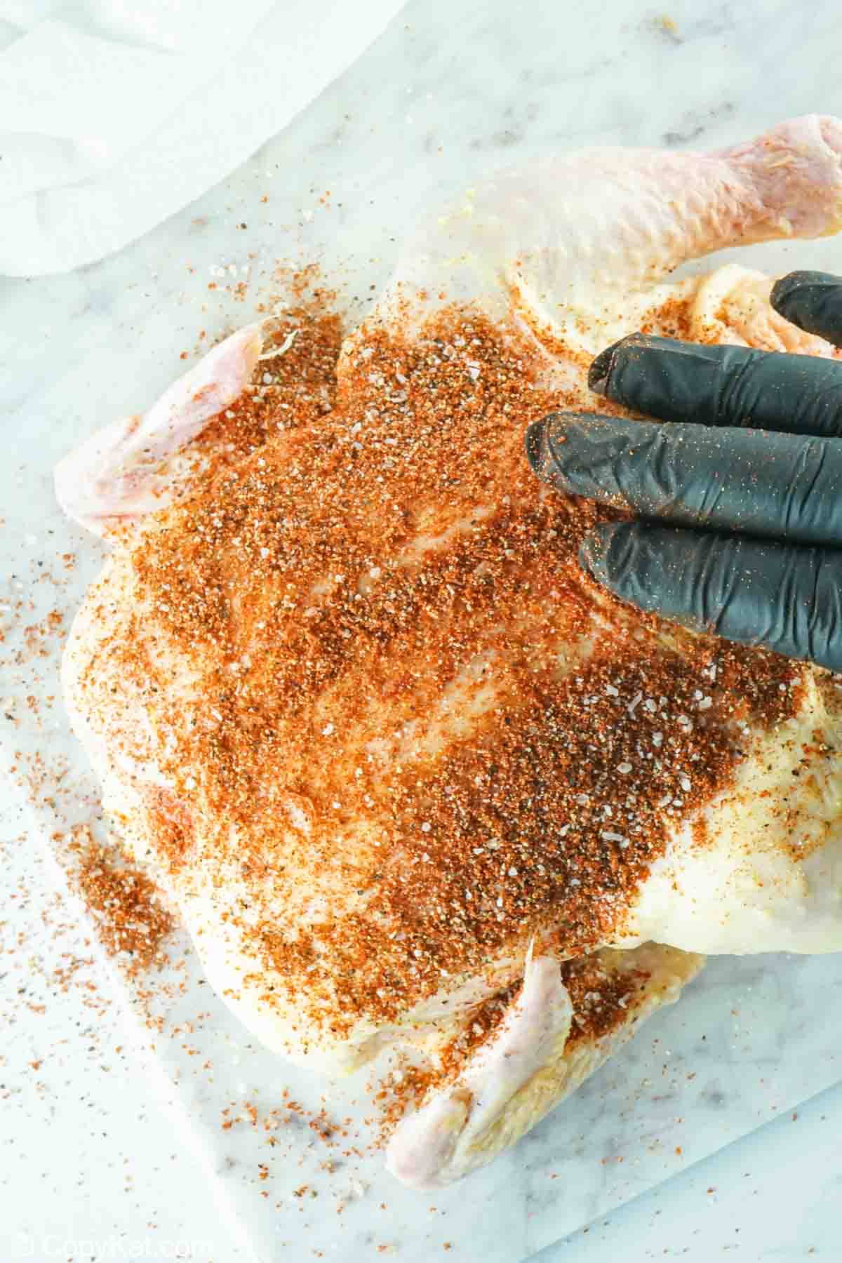 rubbing seasoning on a whole chicken