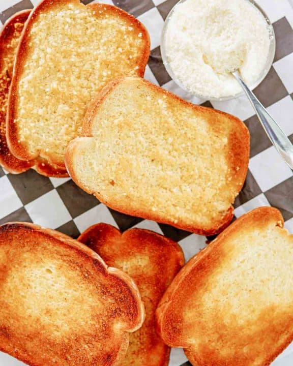 overhead view of texas toast slices and a bowl of parmesan cheese