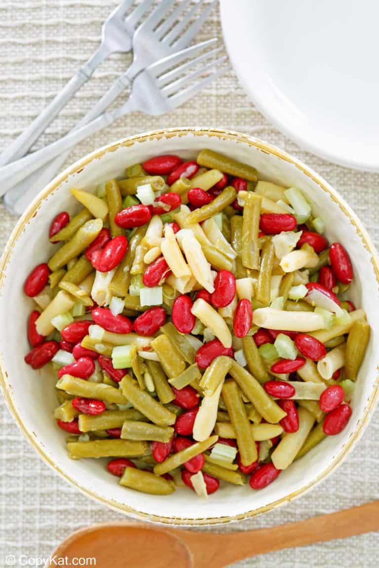 three bean salad, fork, plates, and wooden spoon