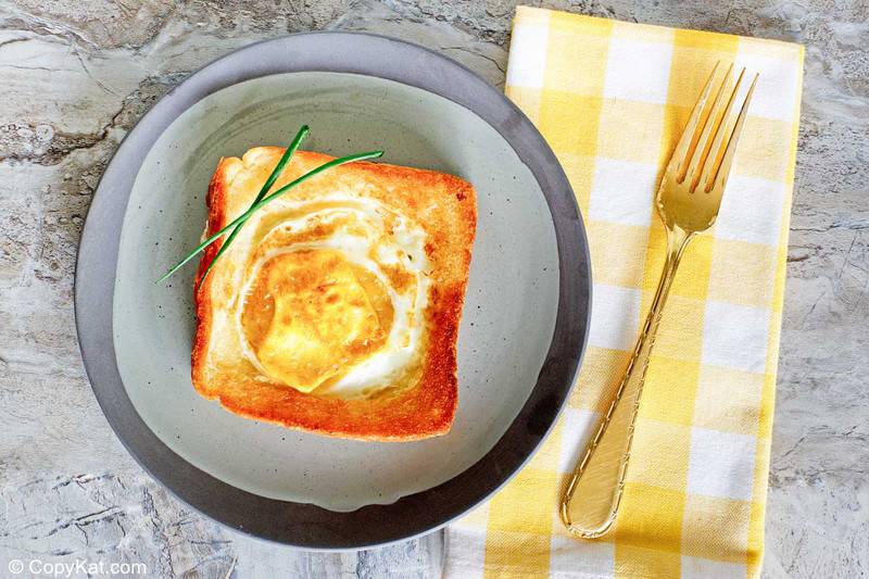 egg in a basket on a plate and a fork on a napkin