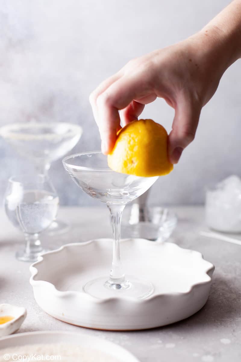 rubbing a cut lemon on the rim of a martini glass