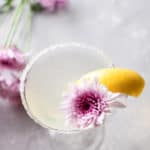 lemon drop martini in a glass rimmed with sugar and garnished with lemon and a flower