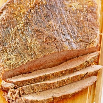 oven baked brisket and a meat fork on a cutting board