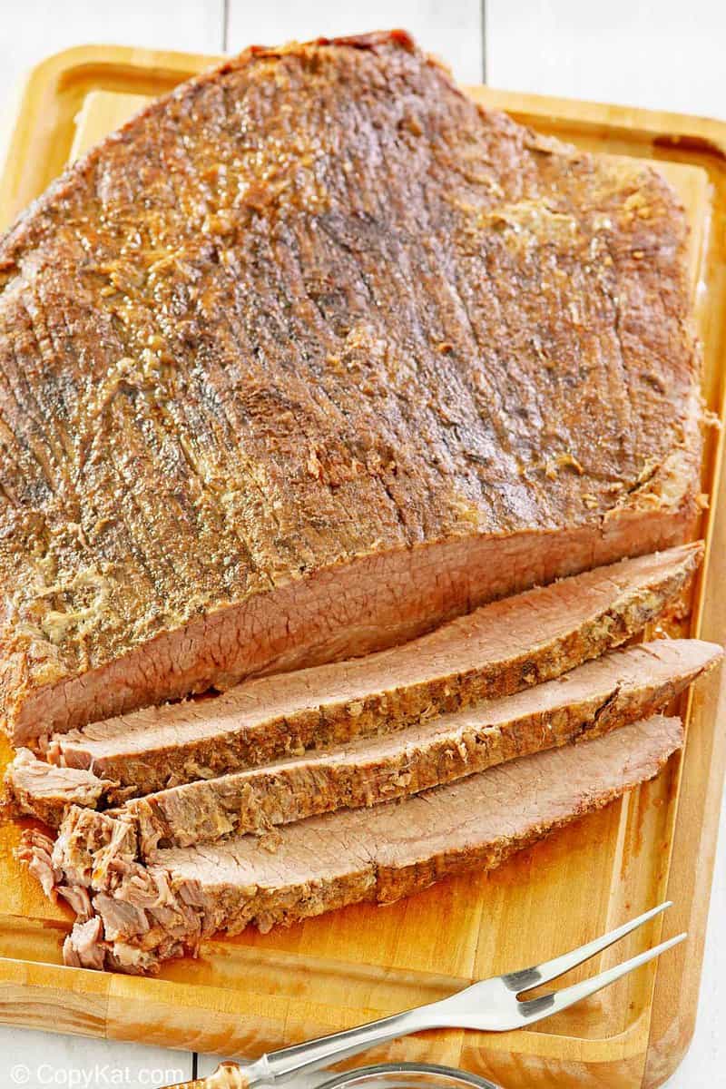 oven baked brisket and a meat fork on a cutting board