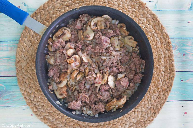 cooked ground beef, sausage, mushrooms, and onions in a skillet