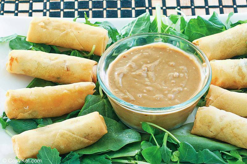 Thai peanut sauce, spring rolls, and arugula on a platter