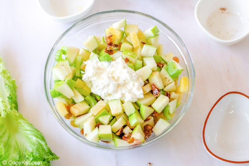 Waldorf salad ingredients and dressing in a glass bowl