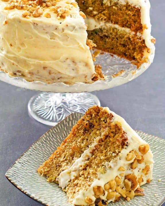 zucchini cake on a cake stand and a slice on a plate