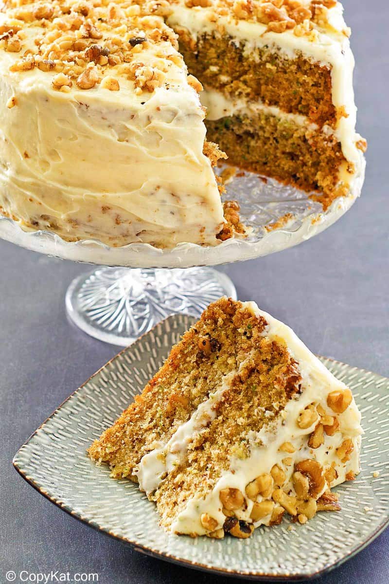 zucchini cake on a cake stand and a slice on a plate