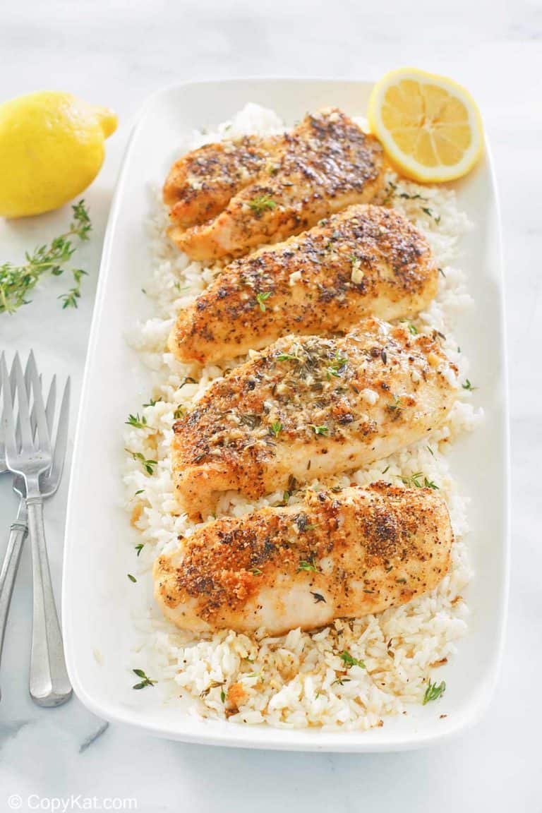 baked lemon pepper chicken with garlic over rice on a platter