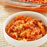 cabbage roll casserole in a bowl in front of the casserole in a baking dish.