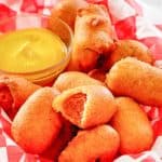 mini corn dogs and mustard in a basket.