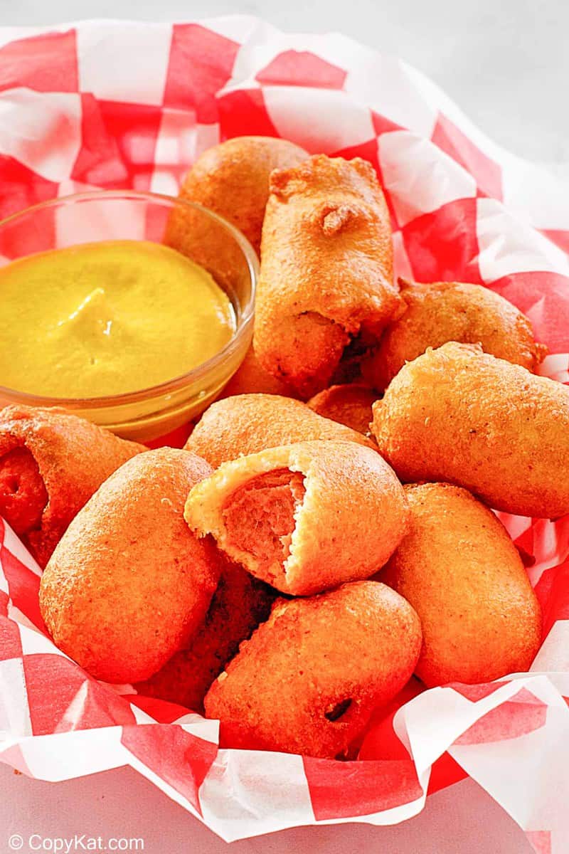 mini corn dogs and mustard in a basket.