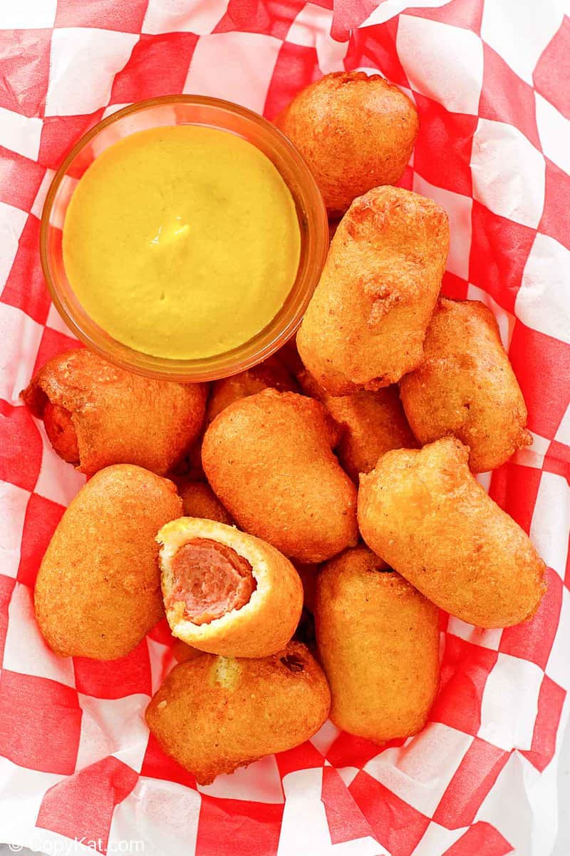 mini corn dogs and mustard on parchment paper.