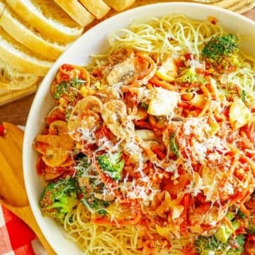 overhead view of homemade Olive Garden capellini primavera next to bread slices and butter