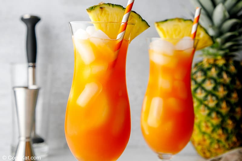 two glasses of spiced rum punch garnished with pineapple