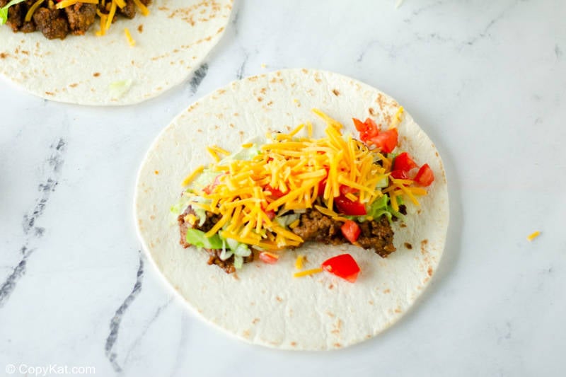 ground beef, lettuce, cheese, and tomatoes on a tortilla