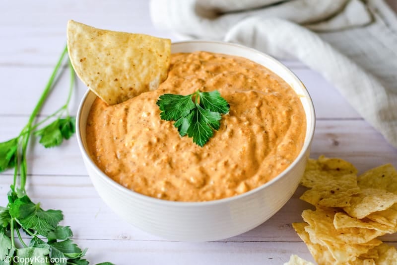 a bowl of taco dip and tortilla chips beside it.