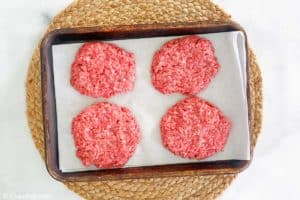four ground beef patties on a tray.