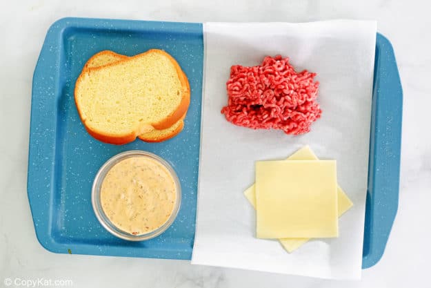 Whataburger patty melt sandwich ingredients on a tray.