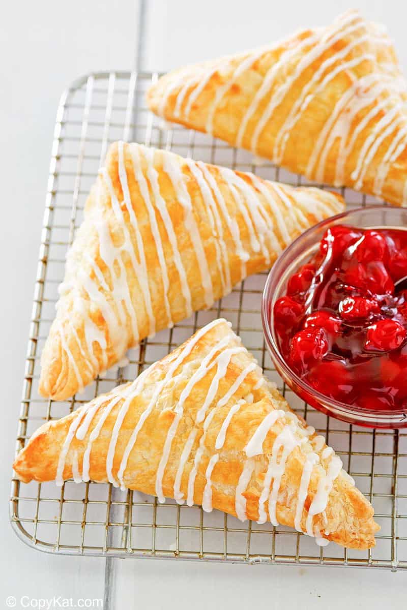 three homemade Arby's cherry turnovers and a small bowl of cherry pie filling