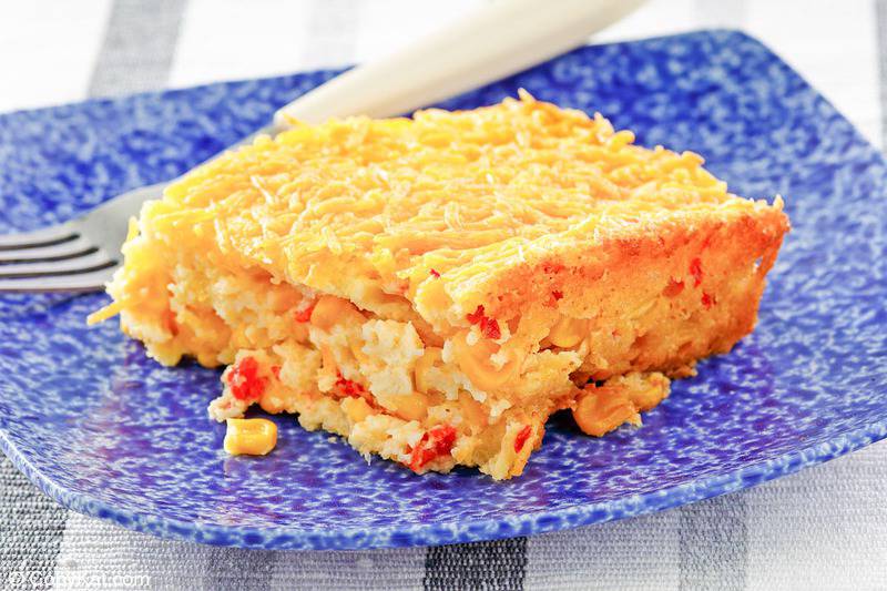 a serving of creamed corn casserole and a fork on a blue plate