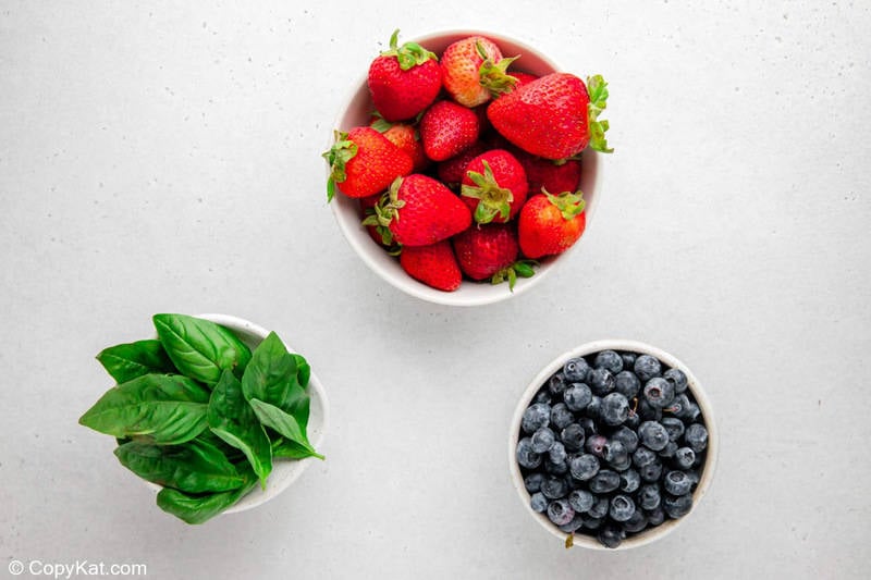 Strawberries, blueberries, and fresh basil leaves.