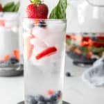 tall glass filled with fruit infused water, fresh fruit, and ice.