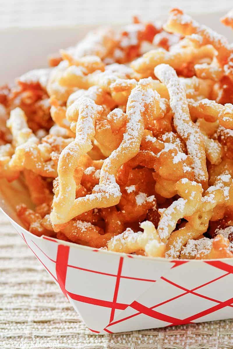 closeup of funnel cake fries in a paper serving dish