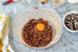 adding egg to brownie cocoa mixture in a bowl