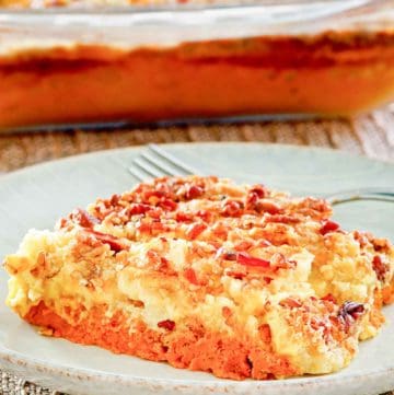 pumpkin dump cake slice on a plate in front of the cake