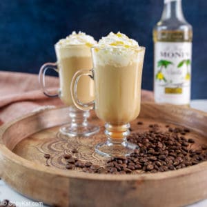 two caramel macchiato coffee drinks topped with whipped cream and caramel sauce